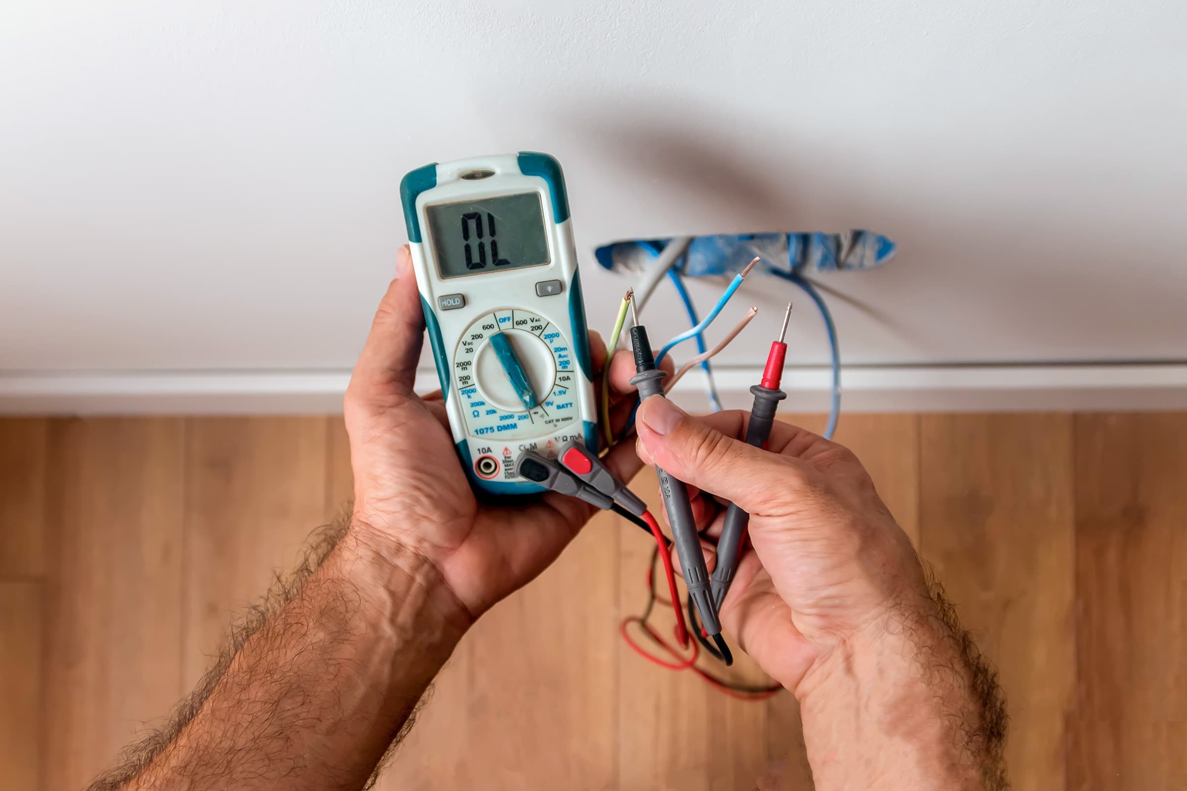 Electrician is using a digital meter to measure the voltage at a power outlet